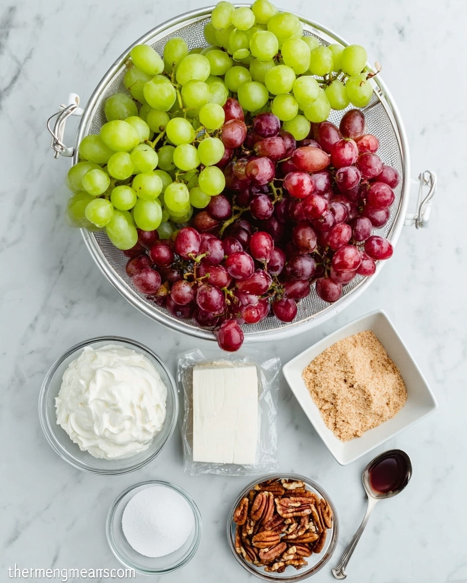 The image shows a white metal colander filled with two layers of grapes: bright green grapes on the top left side and red grapes below them, both looking fresh and plump. Below the colander, arranged in a neat group on a white marbled surface, are several clear bowls and containers holding different ingredients. From left to right, there’s a bowl of white creamy substance, a smaller bowl of white granulated sugar, a round block of white cheese still in its wrapping, a small spoon with a dark liquid, a square white dish filled with light brown crumbly sugar, and a small bowl with chopped pecans. The overall setup is clean and bright, with the ingredients clearly visible and ready for use. Photo taken with an iphone --ar 4:5 --v 7