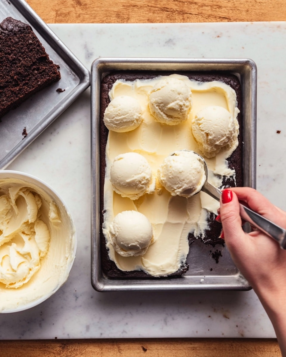 A rectangular metal tray holds a dark brown, moist cake layer. On top, six large scoops of creamy pale yellow frosting are being spread evenly; a woman's hand with red nail polish is using a silver spoon to move the frosting on the right side. To the left of the tray is a larger piece of the dark cake on another metal tray, and in the bottom left corner there is a white bowl containing more of the pale yellow frosting. All is on a white marbled surface. Photo taken with an iphone --ar 4:5 --v 7