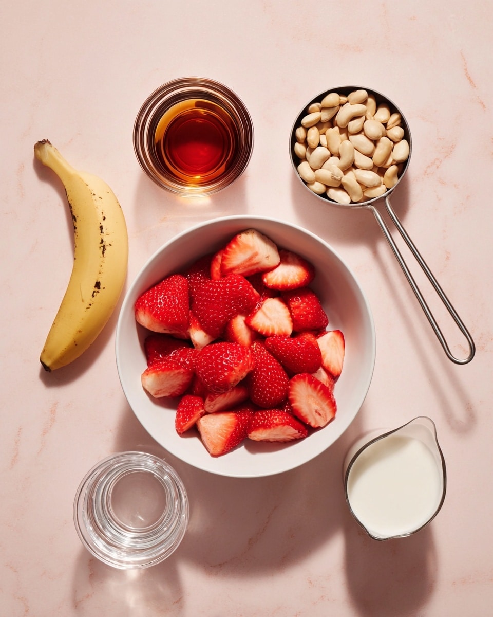 The image shows a clean layout of ingredients on a light pink surface with a white marbled texture. In the center is a white bowl filled with bright red, fresh strawberries, cut into halves and quarters showing their textured seeds and juicy inside. To the top right of the bowl, a metal measuring cup holds pale beige beans, smooth and rounded. Above the beans, a small clear glass cup is filled with a dark amber liquid, shiny and reflective. Below the glass cup is another small clear glass with sparkling clear water. To the left of the bowl, there is a yellow banana segment with a few dark spots. At the bottom of the image, a metal measuring cup contains creamy white milk. All items cast soft shadows, and the layout is neat and minimal. Photo taken with an iphone --ar 4:5 --v 7