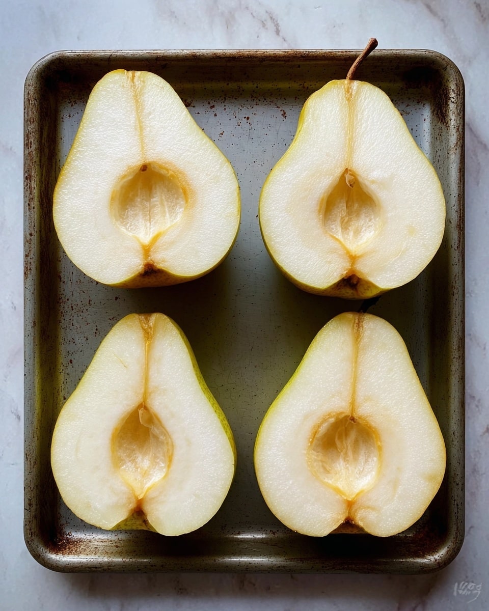 The image shows four halves of two different fruits, two pears and two apples, placed on a flat, slightly worn, dark gray tray. Each fruit half is sliced vertically, revealing the light cream-colored flesh and a hollow seed area in the center of each half. The pears have a light yellow skin with slight brown spotting near the edges, while the apples have a pale yellow to cream skin with smooth texture. The surface beneath the tray is a white marbled texture. The photo taken with an iphone --ar 4:5 --v 7