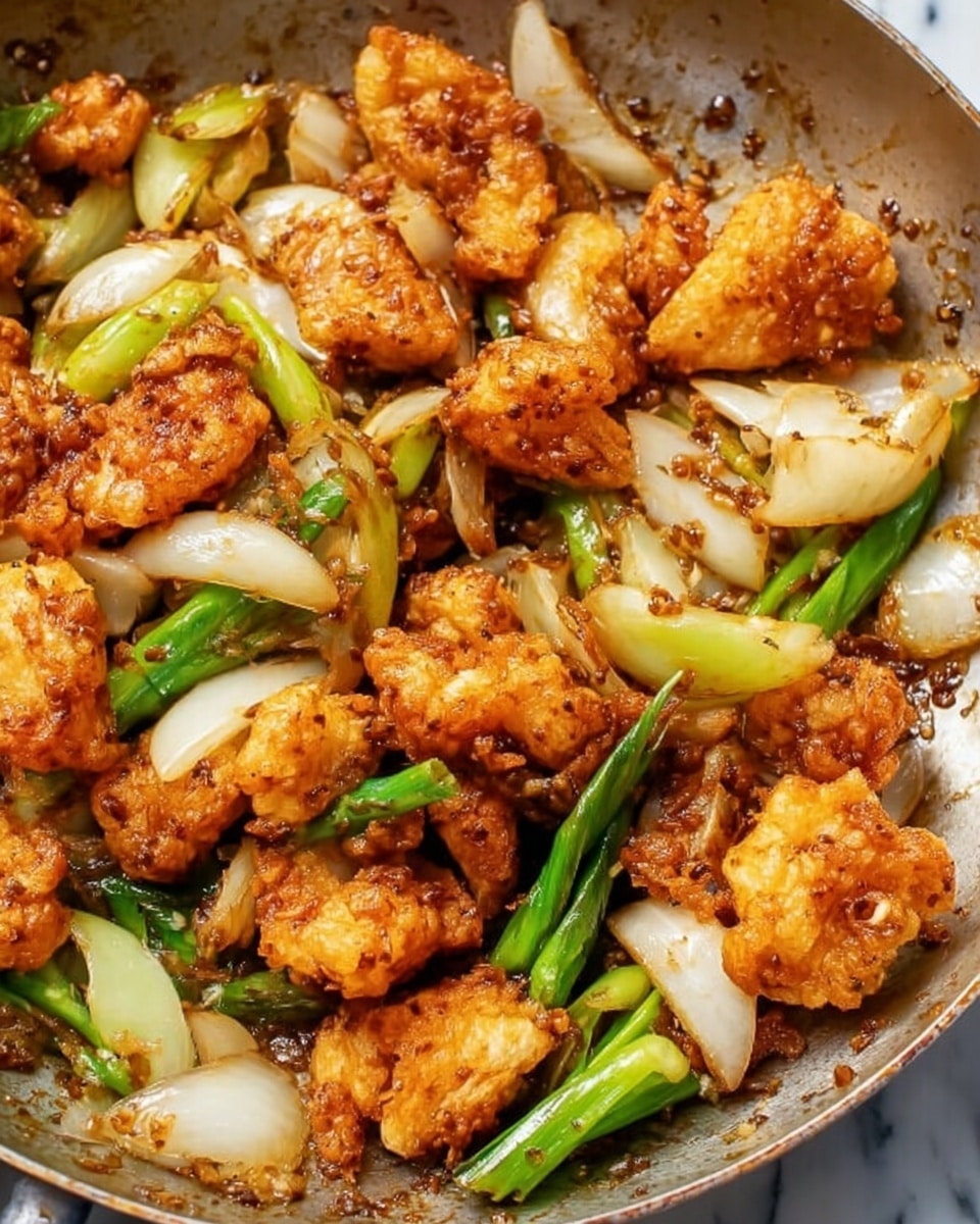 This image shows a close-up of a cooked dish with three main layers: the first layer consists of golden-brown, crispy, irregularly shaped fried pieces that look crunchy and stick together; the second layer is made up of sliced white onions, semi-translucent with a soft texture, spread unevenly between the fried pieces; the third layer includes green onion segments, some light green and some darker, adding a fresh contrast to the warm colors of the fried pieces and onions. The dish is inside a cooking pan with a slightly oily look and scattered bits of seasoning. The background surface is a white marbled texture. Photo taken with an iphone --ar 4:5 --v 7