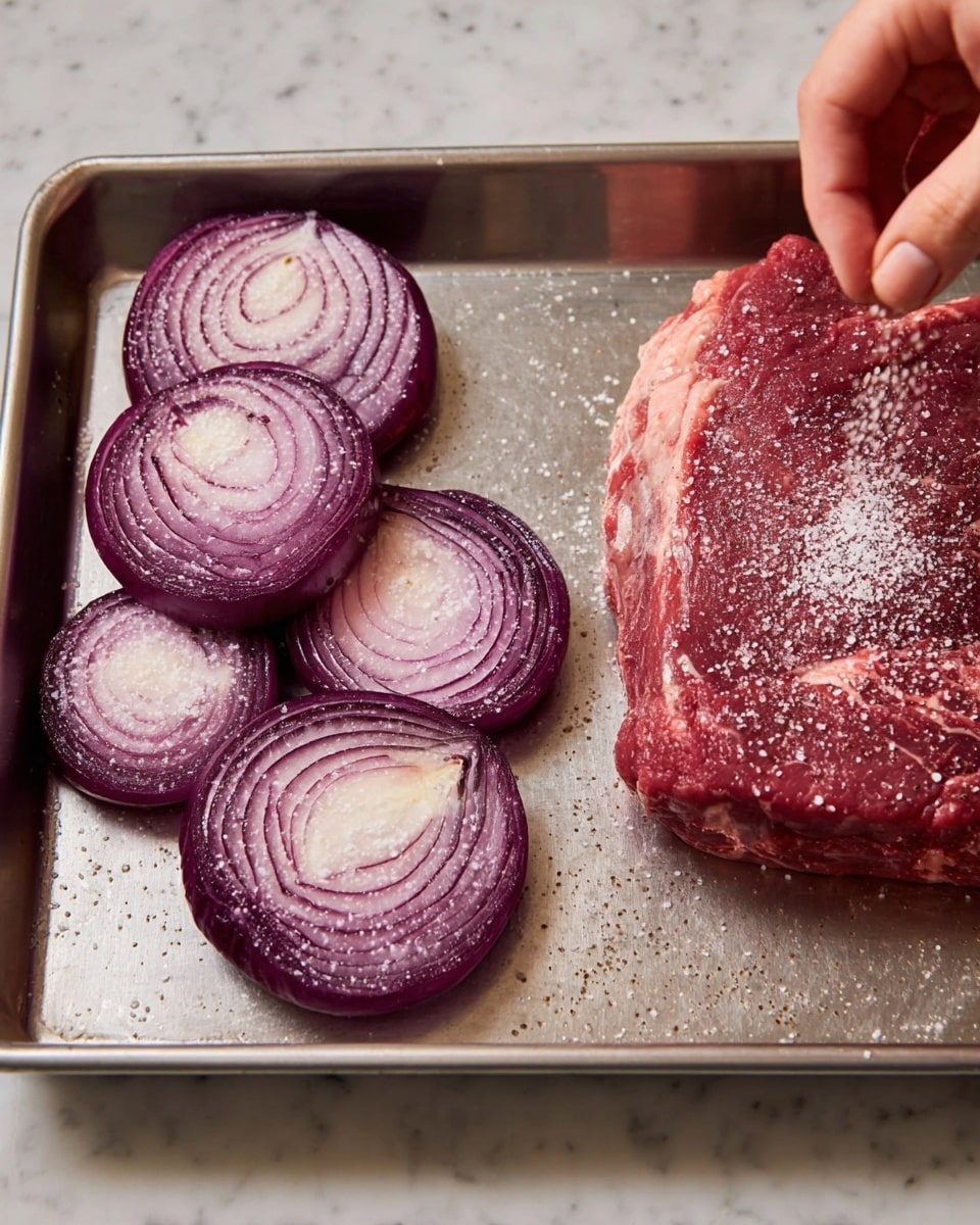 A metal tray holds a thick raw red meat piece on the right side, sprinkled with white salt, with a woman's hand above it adding more salt. On the left side of the tray, there are five round slices of purple onion, each sprinkled lightly with white salt. The tray rests on a white marbled surface, and the lighting highlights the fresh textures of the meat and onions. Photo taken with an iphone --ar 4:5 --v 7