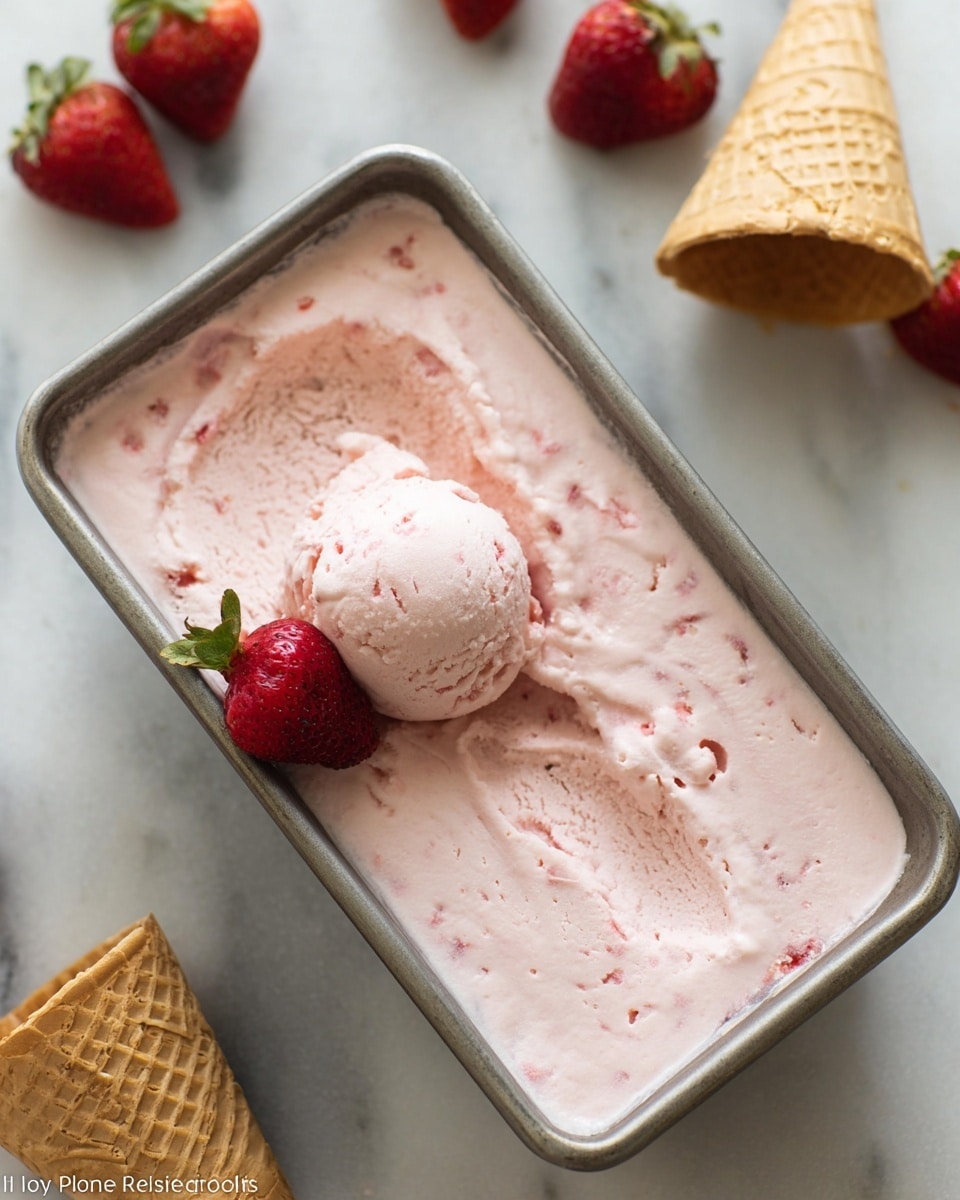 A rectangular metal container filled with smooth, pale pink strawberry ice cream with small bits of strawberry visible inside. One scoop of the ice cream sits near the center, slightly rounded with a soft texture. A whole bright red strawberry with green leaves rests on the ice cream near one corner. In the background, there are two empty waffle cones standing on a white marbled surface along with a few scattered fresh strawberries. The scene is brightly lit. Photo taken with an iphone --ar 4:5 --v 7