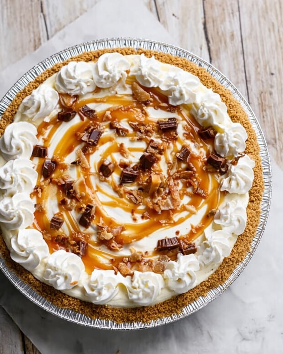 A pie in a silver foil pan is shown from above on a white marbled surface. The pie has a golden-brown crumb crust as the bottom layer. On top, there is a thick white cream layer spread evenly. Swirls of caramel sauce in a rich amber color are drizzled on the cream in a circular pattern. Scattered on the caramel are small pieces of crunchy toffee bits in dark brown and light caramel colors. Around the edge of the pie, there are evenly spaced white whipped cream rosettes forming a ring. Photo taken with an iphone --ar 4:5 --v 7