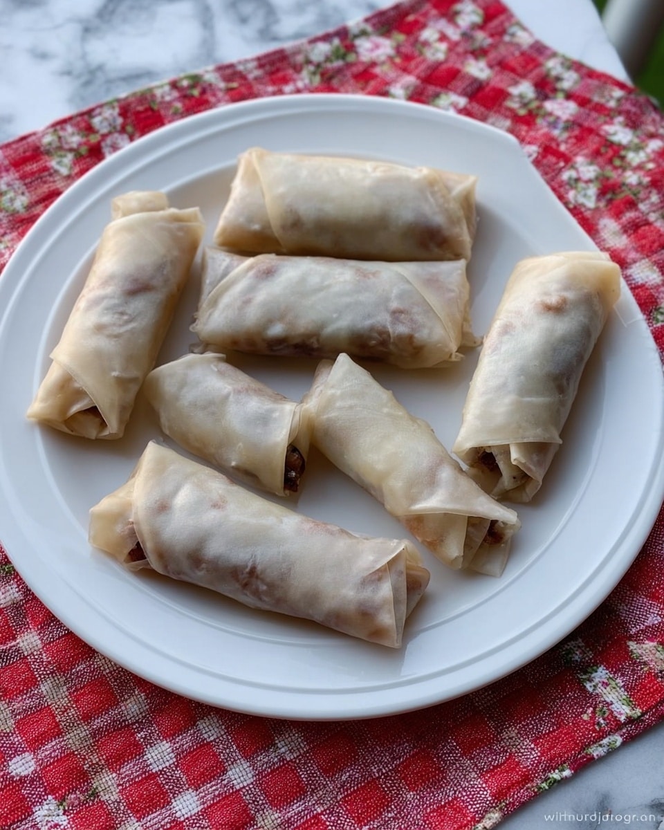 A white plate holds seven rolled spring rolls arranged loosely across its surface. Each roll has a pale, slightly translucent wrapper with visible folds and soft texture, showing a dark filling inside with hints of brown and purples. The rolls vary in size, with some longer and more tightly wrapped while others are shorter with loose ends. The plate sits on a red and white checkered cloth with a floral pattern underneath, resting on a white marbled surface. photo taken with an iphone --ar 4:5 --v 7