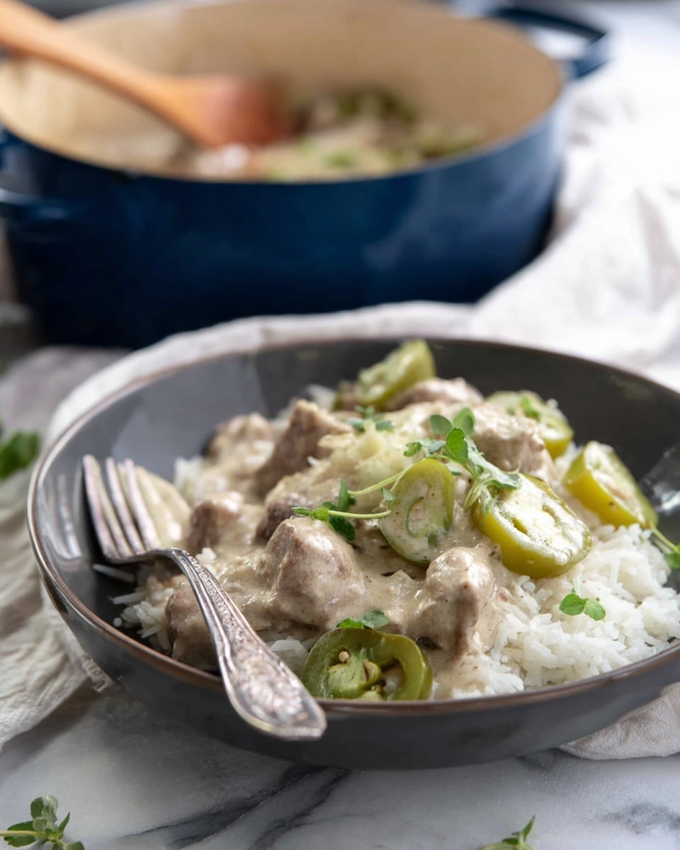 A close-up of a wooden spoon holding cooked slices of light brown meat, thin white onion rings, and bright green bell pepper pieces with melted white cheese stretching between the spoon and the food below. Below the spoon is a white bowl filled with the same ingredients—light brown meat strips, white onions, green bell peppers—mixed in a creamy, light sauce. The background is a white marbled surface. Photo taken with an iphone --ar 4:5 --v 7