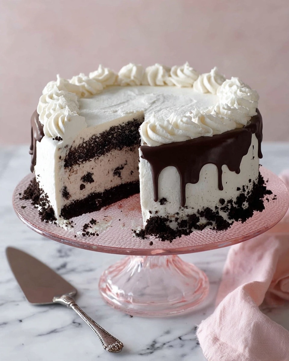 A round cake with three visible layers sits on a clear pink glass cake stand over a white marbled surface. The bottom layer is dark chocolate, the middle is light cream with small dark cookie pieces mixed in, and the top is smooth white frosting. Around the side of the cake near the bottom, there are crushed dark cookie crumbs. A thick, dark chocolate drip runs down from the edge of the top. The top edge is decorated with white frosting in a wavy pattern. A slice of the cake has been removed, showing the inside clearly. Nearby, there is a silver cake server and a soft pink cloth. Photo taken with an iphone --ar 4:5 --v 7