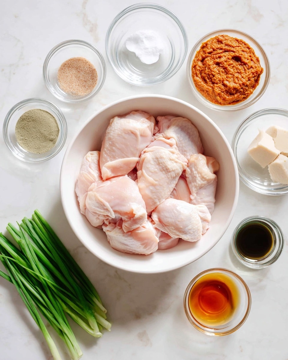 A white bowl filled with six raw, pale pink chicken pieces sits in the center of a white marbled surface. Surrounding the bowl are eight small clear glass containers holding different ingredients: light brown coarse salt on the left, next to clear liquid, a bowl with thick orange-red paste at the top, a bowl with two white tablets and a small beige piece to the right, a small bowl with a beige chunk below, and two cups with dark and amber liquids at the bottom. A clear bowl of bright green cut scallions is on the lower left. The scene is bright and clean, showing all ingredients neatly arranged. photo taken with an iphone --ar 4:5 --v 7