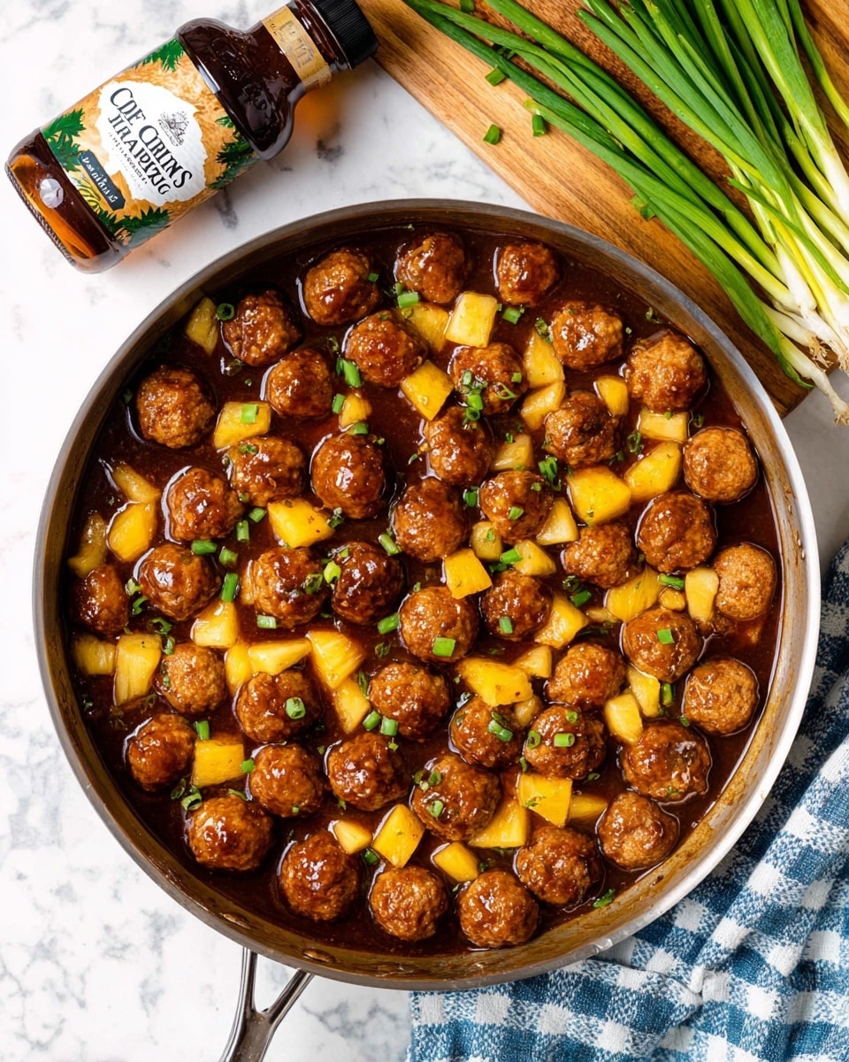 A round metal pan is filled with two layers of food. The bottom layer has small, brown meatballs, some coated with a shiny dark brown sauce, spread evenly across the pan. The top layer consists of bright yellow pineapple chunks scattered mainly in the middle, covering part of the meatballs. The background surface is white with a marbled texture. photo taken with an iphone --ar 4:5 --v 7