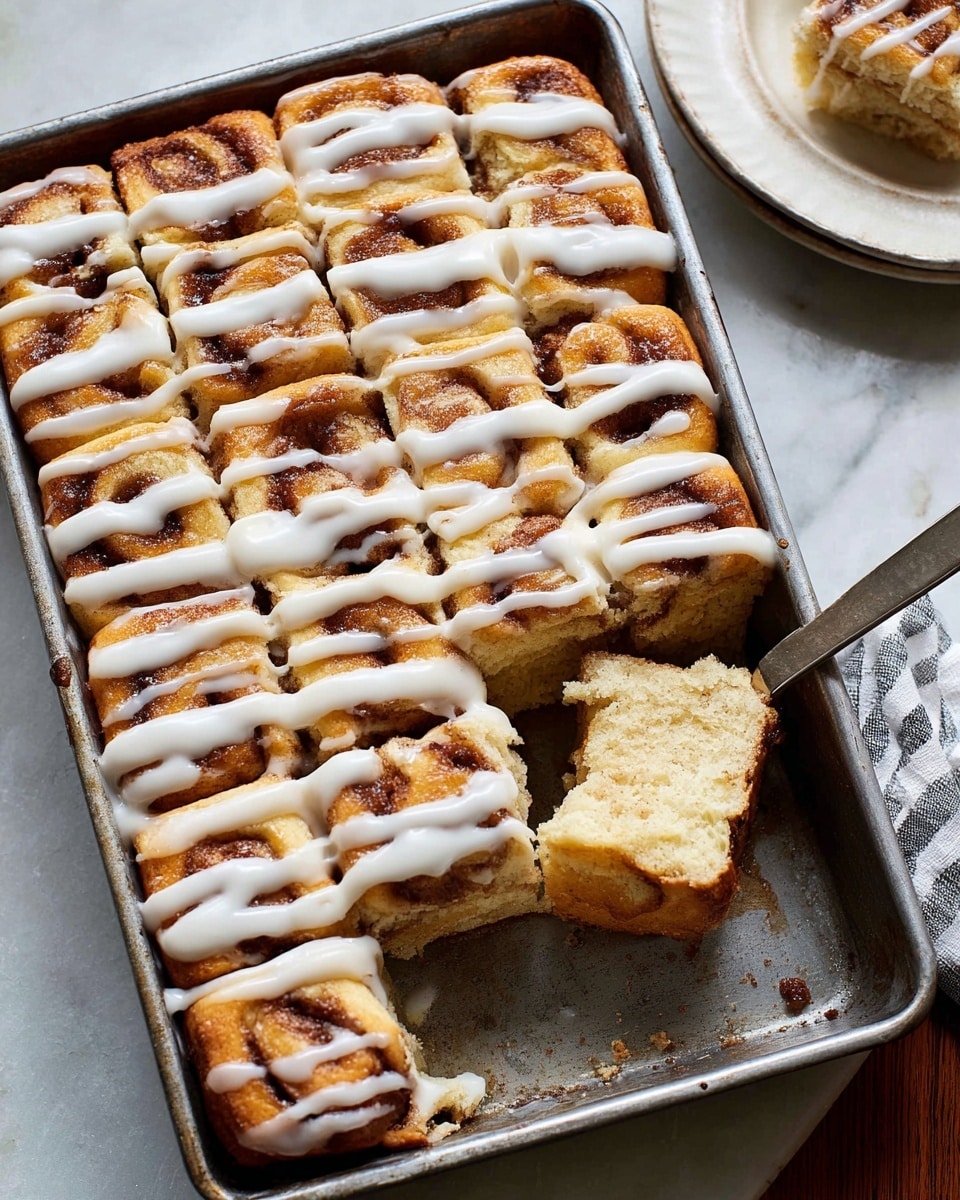 A tray of cinnamon roll sticks is shown on brown parchment paper with a white marbled surface underneath. The sticks are golden brown with a slightly crisp, textured top and soft, light inner layers visible in one piece turned on its side. A thick white glaze is drizzled in diagonal lines across all the sticks. To the right, a butter knife with some glaze on it rests on the parchment. On the left edge, part of a white bowl with extra glaze is seen. The image has warm tones and a cozy feel photo taken with an iphone --ar 4:5 --v 7