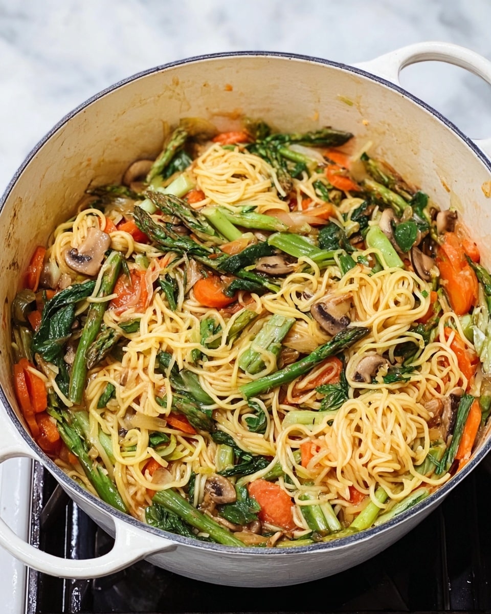 A large white pot filled with a colorful noodle dish sits on a white marbled surface. The dish has three main layers: at the bottom is a mix of light yellow noodles that look soft and mixed with a light sauce; scattered throughout are bright orange sliced carrots and small pieces of light brown mushrooms; on top, there are asparagus pieces and wilted green leafy vegetables adding a fresh green color. The noodles are twisted and arranged loosely with the vegetables spread evenly, creating a vibrant, mixed texture. Photo taken with an iphone --ar 4:5 --v 7