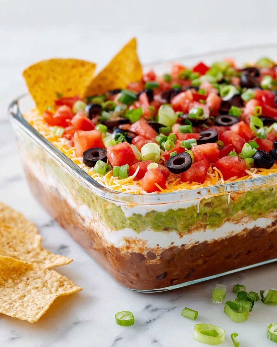 The image shows six stages of a layered dip in a clear glass white rectangular dish on a white marbled surface. Layer one is a smooth, light brown refried bean spread filling the dish evenly. Layer two is a thick, green guacamole with visible small pieces of herbs and spices, spread smoothly over the brown layer. Layer three is a creamy, light beige sour cream layer, spread evenly. Layer four is a dense layer of finely shredded yellow and white cheese covering the dip. Layer five adds finely chopped bright red tomatoes scattered over the cheese. Layer six is the top layer sprinkled with more chopped tomatoes, sliced black olives, and bits of green onion, giving a colorful and textured finish to the dip. Each layer is clearly visible through the glass sides of the dish. photo taken with an iphone --ar 4:5 --v 7