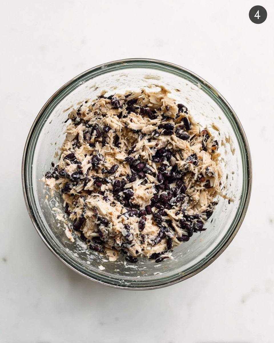 A clear glass bowl sits on a white marbled surface filled with a mixed dish that has two main colors: light beige and dark purple. The mix looks soft and chunky, with small shredded pieces of what seems like cooked light-colored meat or vegetable, and many small dark purple beans or seeds scattered throughout. The mixture fills the bowl almost to the top, and the sides of the bowl show some residue of the mix. The background is plain white with a small round label showing the number 4 at the top right corner. Photo taken with an iphone --ar 4:5 --v 7