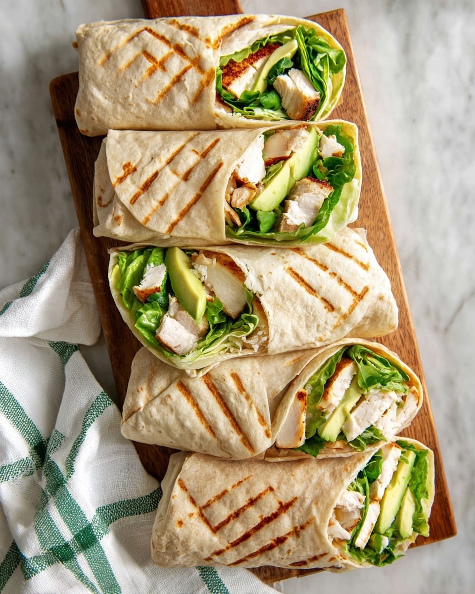 Five grilled wraps are placed on a wooden board over a white marbled surface. Each wrap has a light golden-brown soft tortilla with parallel grill marks on top. Inside, the wraps are layered with bright green leafy lettuce, pieces of white grilled chicken with a light brown sear, and slices of pale green avocado. Some wraps are cut in half, showing the layers clearly from the side. A white cloth with green stripes is seen beside the wooden board. Photo taken with an iphone --ar 4:5 --v 7
